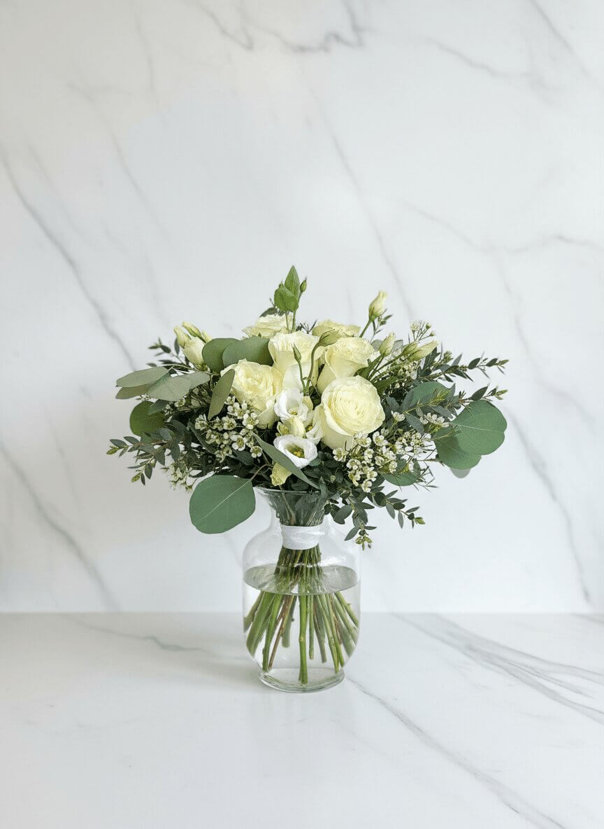 Bouquet de fleurs blanc avec roses et eucalyptus en vase par fleuriste à Beloeil
