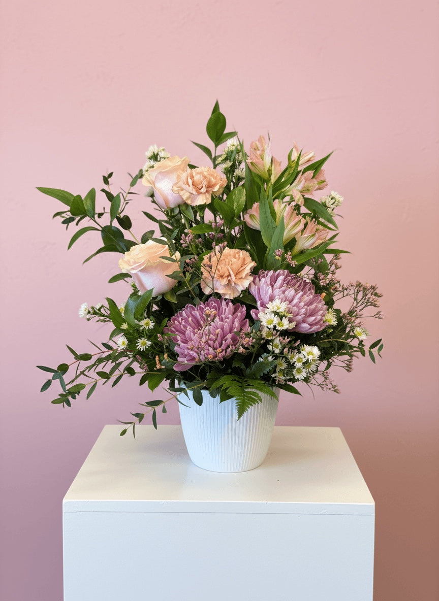 Bouquet de fleurs pastel rose, mauve et pêche avec feuillage dans un pot blanc, style champêtre élégant Fleuriste Beloeil 